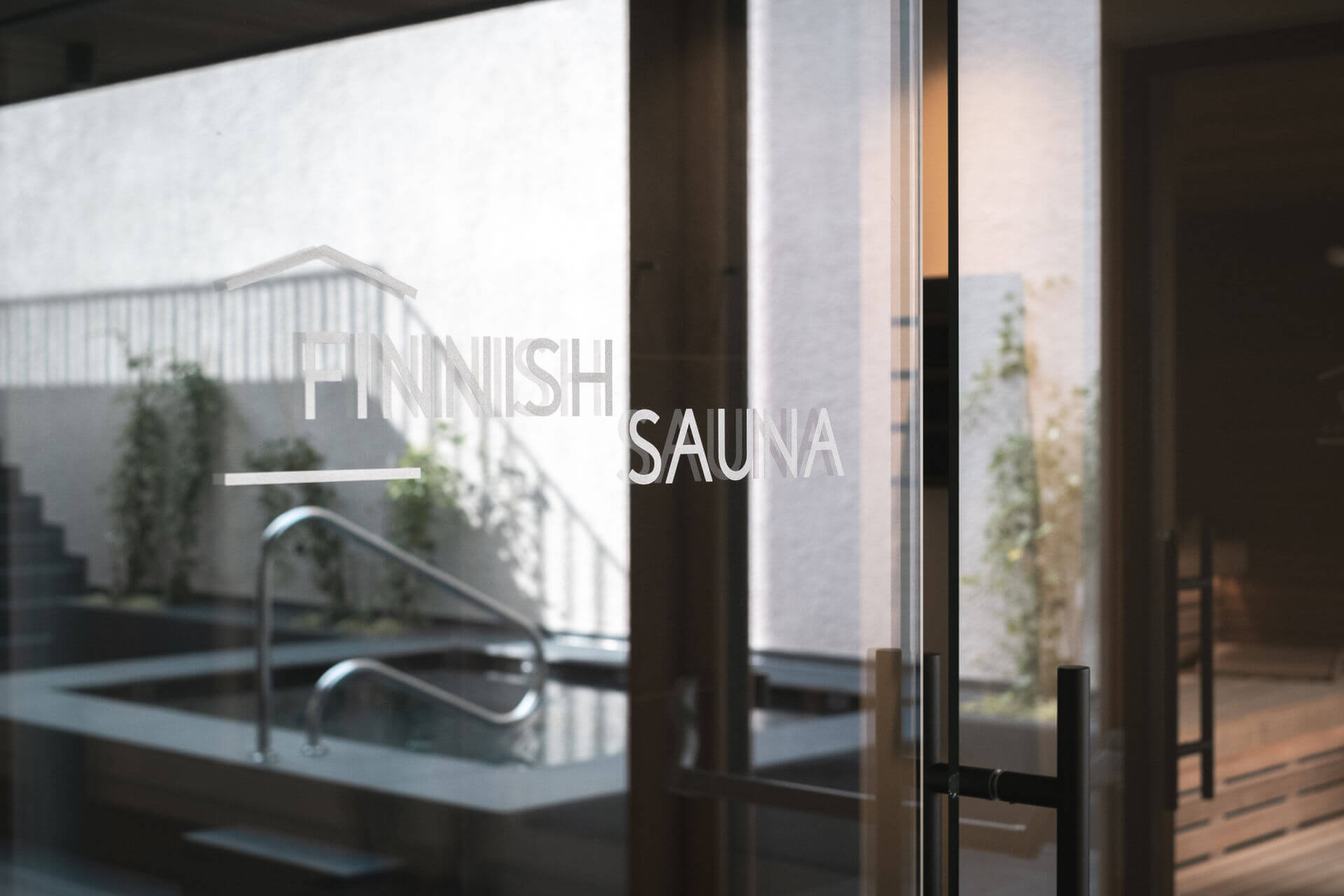 The glass door of the Finnish sauna reflects the outdoor whirlpool - Gisse Zwölf