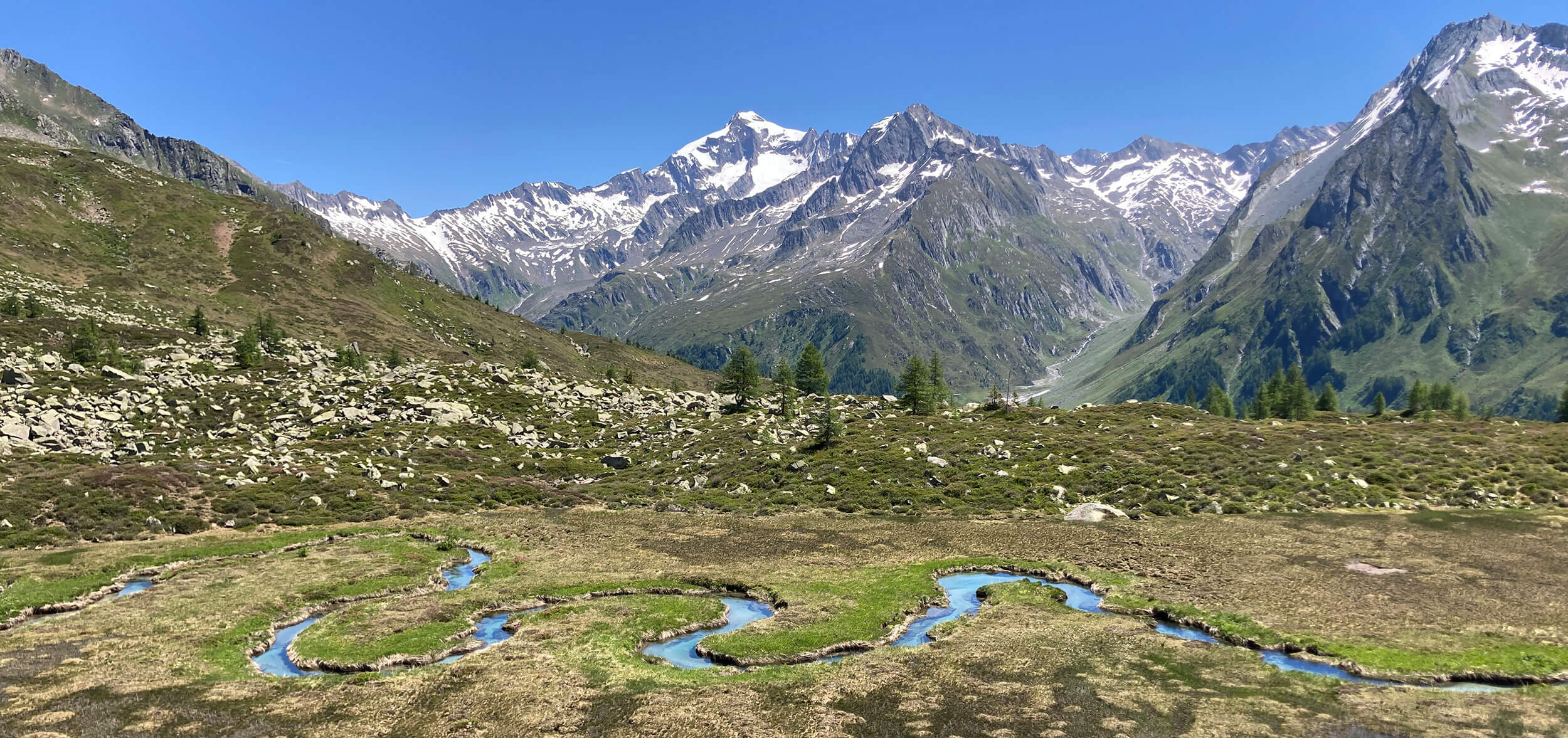 Turquoise winding river with mountains in the background - Gisse Zwölf